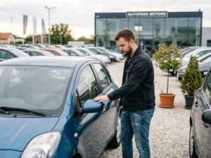 Jeune homme examine une voiture en concession automobile